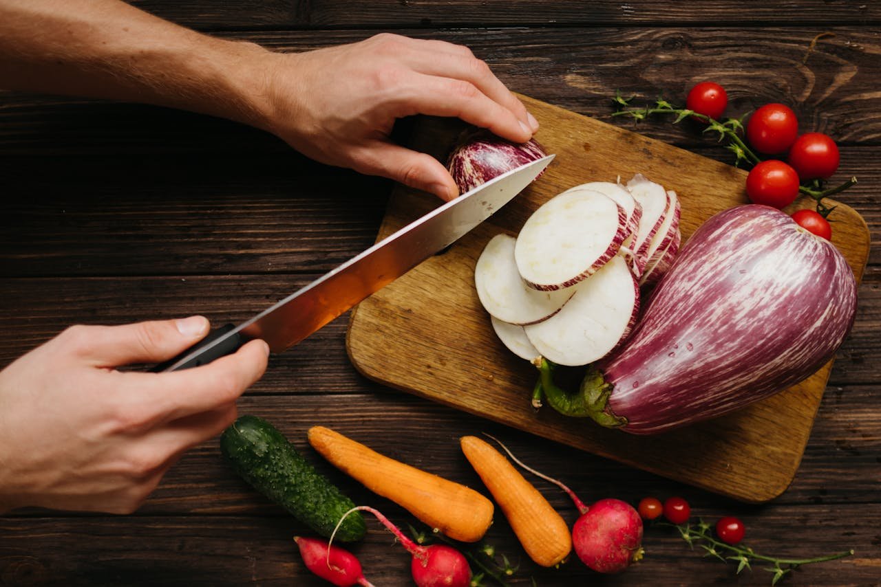 Person Slicing White Onion on Brown Wooden Chopping Board